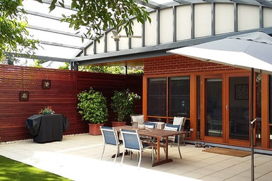 This is an example of a mid-sized transitional backyard verandah in Adelaide with concrete pavers and a roof extension.