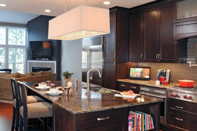 Example of a mid-sized minimalist l-shaped medium tone wood floor eat-in kitchen design in Columbus with a farmhouse sink, shaker cabinets, medium tone wood cabinets, granite countertops, gray backsplash, glass tile backsplash, stainless steel appliances and an island