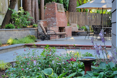 На фото: большой летний регулярный сад на заднем дворе в классическом стиле с уличным камином, полуденной тенью и мощением тротуарной плиткой
