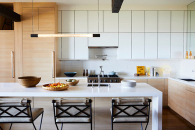 Inspiration for a contemporary l-shaped kitchen in San Francisco with an undermount sink, flat-panel cabinets, white cabinets, white splashback, medium hardwood floors, with island, brown floor and white benchtop.