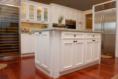 Photo of a mid-sized traditional eat-in kitchen in Miami with recessed-panel cabinets, white cabinets, subway tile splashback, stainless steel appliances, medium hardwood floors, with island and a double-bowl sink.