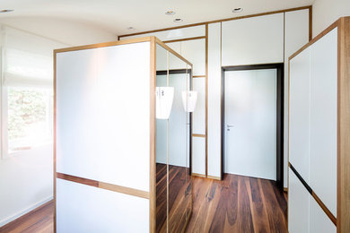 Mittelgroßes, Neutrales Mid-Century Ankleidezimmer mit Ankleidebereich, flächenbündigen Schrankfronten und dunklem Holzboden in Frankfurt am Main