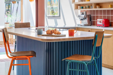 This is an example of a large bohemian single-wall open plan kitchen in Other with an integrated sink, flat-panel cabinets, medium wood cabinets, wood worktops, red splashback, terracotta splashback, black appliances, concrete flooring, an island and grey floors.