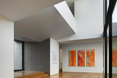 Entryway - large modern light wood floor entryway idea in Charlotte with white walls and a glass front door