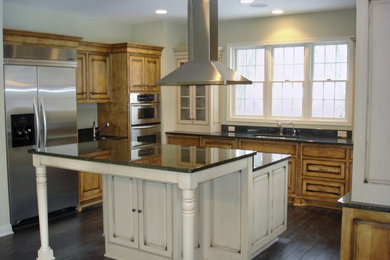 Inspiration for a mid-sized timeless u-shaped dark wood floor kitchen remodel in Orange County with an undermount sink, raised-panel cabinets, medium tone wood cabinets, granite countertops and stainless steel appliances