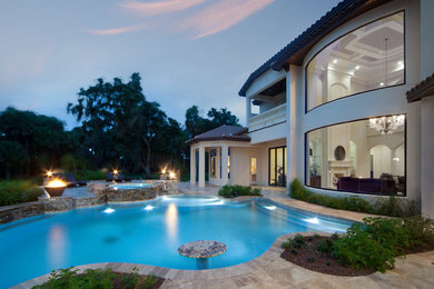 Expansive mediterranean backyard custom-shaped natural pool in Orlando with a water feature and natural stone pavers.