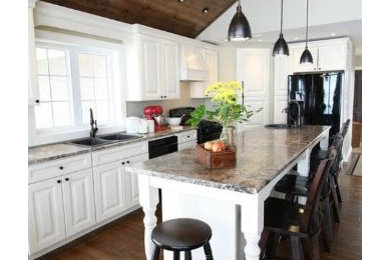 Inspiration for a mid-sized transitional l-shaped medium tone wood floor open concept kitchen remodel in Toronto with a drop-in sink, raised-panel cabinets, white cabinets, laminate countertops, black appliances and an island