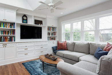 Example of a mid-sized trendy open concept medium tone wood floor family room design in Seattle with beige walls, no fireplace and a media wall