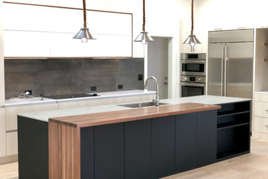 Inspiration for a large contemporary l-shaped open plan kitchen in Denver with a drop-in sink, flat-panel cabinets, beige cabinets, quartz benchtops, grey splashback, ceramic splashback, stainless steel appliances, light hardwood floors, with island, grey floor and grey benchtop.