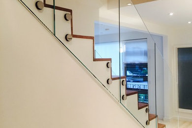 Large modern straight staircase in New York with glass railing.