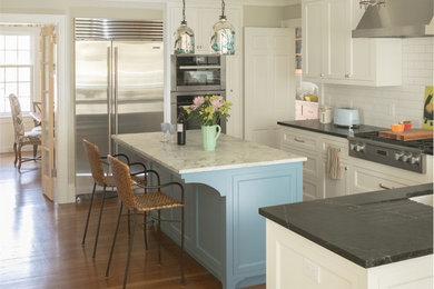 Eat-in kitchen - mid-sized traditional medium tone wood floor and brown floor eat-in kitchen idea in New York with stainless steel appliances, an undermount sink, white cabinets, soapstone countertops, white backsplash, ceramic backsplash, an island and recessed-panel cabinets