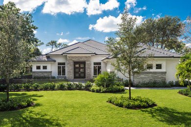 Mid-sized transitional one-storey stucco grey house exterior in Miami with a hip roof.