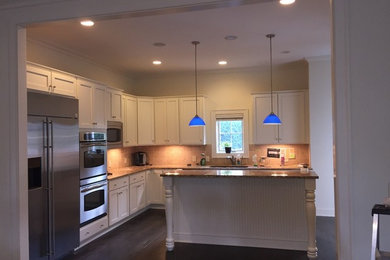 Example of a mid-sized classic l-shaped dark wood floor and brown floor enclosed kitchen design in Columbus with an undermount sink, shaker cabinets, white cabinets, granite countertops, brown backsplash, ceramic backsplash, stainless steel appliances, an island and brown countertops