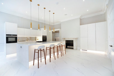 Photo of a modern kitchen in London with an integrated sink, white cabinets, an island, white worktops, feature lighting and white floors.