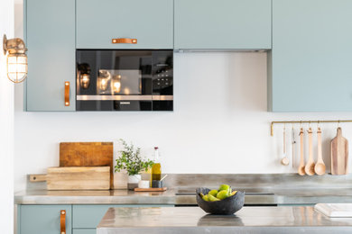 Modelo de cocina urbana con puertas de armario azules, encimera de acero inoxidable, electrodomésticos negros, una isla y encimeras grises