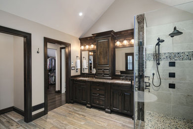 Inspiration for a large timeless master ceramic tile ceramic tile and brown floor bathroom remodel in Philadelphia with raised-panel cabinets, dark wood cabinets, a one-piece toilet, beige walls, an undermount sink, granite countertops, a hinged shower door and brown countertops