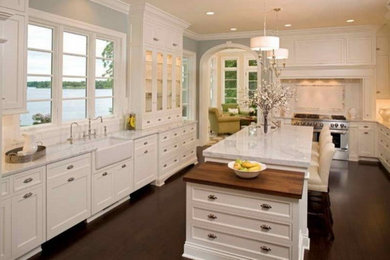 Example of a large arts and crafts u-shaped dark wood floor enclosed kitchen design in DC Metro with a farmhouse sink, beaded inset cabinets, white cabinets, marble countertops, stainless steel appliances and an island