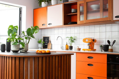 Design ideas for a medium sized retro kitchen in Sussex with flat-panel cabinets, composite countertops, white splashback, ceramic splashback, dark hardwood flooring, an island, white worktops, a feature wall, orange cabinets and exposed beams.