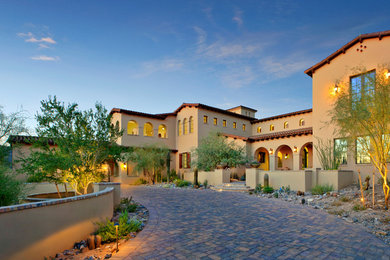 This is an example of a large mediterranean three-storey stucco beige exterior in Phoenix.
