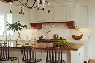 Example of a mid-sized classic l-shaped medium tone wood floor eat-in kitchen design in New York with an undermount sink, recessed-panel cabinets, white cabinets, marble countertops, white backsplash, stone slab backsplash, stainless steel appliances and an island