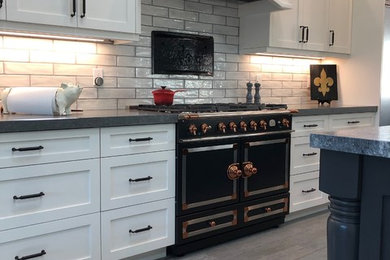Example of a farmhouse brown floor kitchen design in Orange County with shaker cabinets, white cabinets, granite countertops, an island and gray countertops