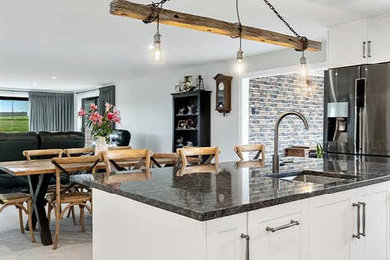 Imagen de cocina comedor actual grande con salpicadero blanco, electrodomésticos de acero inoxidable y una isla