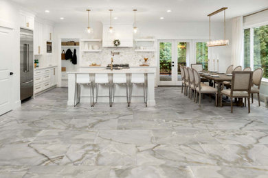 Elegant porcelain tile and gray floor kitchen photo in DC Metro with shaker cabinets, white cabinets, quartzite countertops, beige backsplash, stainless steel appliances, an island and white countertops
