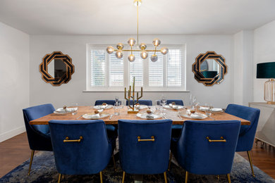 Photo of a medium sized contemporary dining room in Surrey with white walls, dark hardwood flooring and feature lighting.