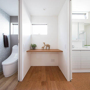 Immagine di un bagno di servizio minimalista con ante lisce, ante bianche, WC monopezzo, pareti bianche, pavimento in sughero, lavabo integrato, pavimento marrone e top bianco