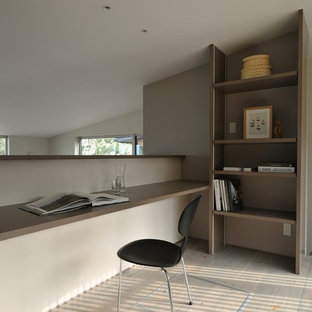 Modern home office and library in Other with grey walls, painted wood flooring, a built-in desk and grey floors.