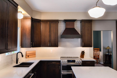 Mid-sized elegant l-shaped dark wood floor and brown floor eat-in kitchen photo in Other with an undermount sink, shaker cabinets, dark wood cabinets, quartz countertops, white backsplash, ceramic backsplash, stainless steel appliances, an island and white countertops