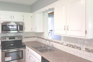 Mid-sized elegant kitchen photo in Kansas City with a double-bowl sink, raised-panel cabinets, white cabinets, granite countertops, white backsplash, subway tile backsplash and stainless steel appliances
