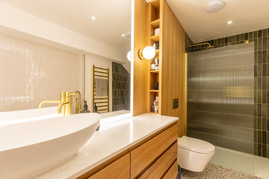 Photo of a large modern ensuite bathroom in London with recessed-panel cabinets, light wood cabinets, a freestanding bath, a walk-in shower, a wall mounted toilet, green tiles, porcelain tiles, white walls, porcelain flooring, a console sink, marble worktops, white floors, an open shower, white worktops, a feature wall, a single sink, a floating vanity unit, a wallpapered ceiling and wood walls.