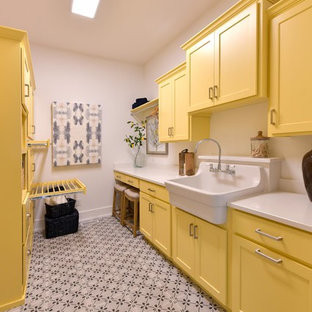 Photo of a classic separated utility room in Cleveland with a belfast sink, shaker cabinets, yellow cabinets, white walls, multi-coloured floors and white worktops.