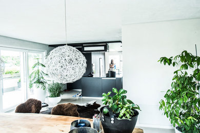 Mittelgroße, Offene, Zweizeilige Moderne Küche mit Doppelwaschbecken, flächenbündigen Schrankfronten, schwarzen Schränken, Granit-Arbeitsplatte, Küchenrückwand in Schwarz, Küchengeräten aus Edelstahl, Betonboden, Kücheninsel, grauem Boden und schwarzer Arbeitsplatte in Stuttgart