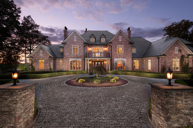 Elegant red two-story brick house exterior photo in Bridgeport with a hip roof and a shingle roof