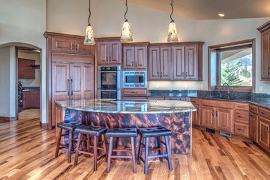 Kitchen - large rustic medium tone wood floor kitchen idea in Denver with an undermount sink, raised-panel cabinets, medium tone wood cabinets, granite countertops, stainless steel appliances and an island