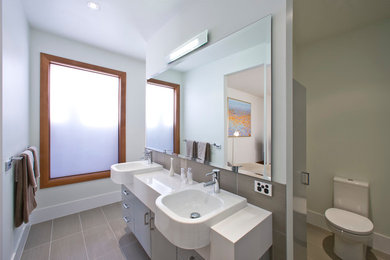 This is an example of a mid-sized contemporary master bathroom in Melbourne with a console sink, open cabinets, grey cabinets, engineered quartz benchtops, an open shower, a two-piece toilet, gray tile, porcelain tile, yellow walls and porcelain floors.