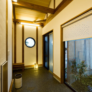 他の地域の引き戸アジアンスタイルのおしゃれな玄関 (ベージュの壁、黒い床) の写真