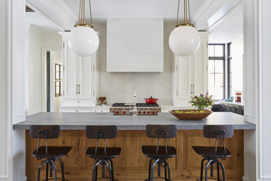 Huge elegant u-shaped light wood floor and brown floor open concept kitchen photo with a farmhouse sink, recessed-panel cabinets, white cabinets, quartz countertops, white backsplash, stone slab backsplash, stainless steel appliances, an island and gray countertops