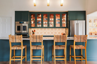 Transitional galley medium tone wood floor and brown floor kitchen photo in Baltimore with an undermount sink, shaker cabinets, green cabinets, multicolored backsplash, stainless steel appliances, an island and white countertops