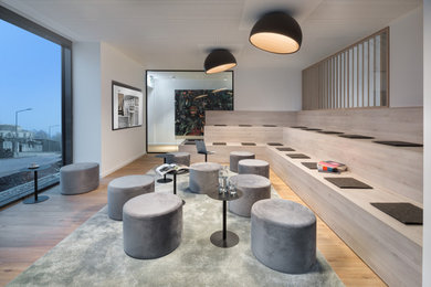 Esempio di un soggiorno moderno con pareti bianche, pavimento in legno massello medio e TV a parete