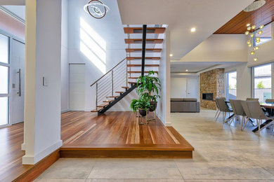 This is an example of a large contemporary foyer in Sydney with white walls, light hardwood floors, a pivot front door, a white front door and brown floor.