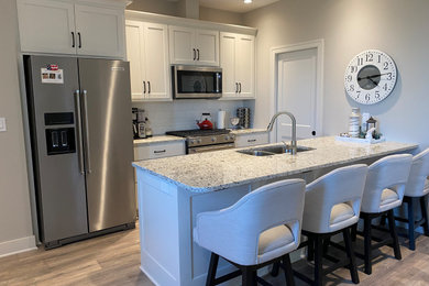 Inspiration for a small transitional single-wall brown floor eat-in kitchen remodel in Kansas City with an undermount sink, shaker cabinets, white cabinets, granite countertops, white backsplash, stainless steel appliances, an island and gray countertops