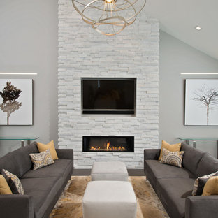 Inredning av ett modernt vardagsrum, med grå väggar, en bred öppen spis och en väggmonterad TV