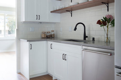 Example of a large trendy galley light wood floor and brown floor eat-in kitchen design in Hawaii with shaker cabinets, white cabinets, white backsplash, subway tile backsplash, stainless steel appliances and an integrated sink