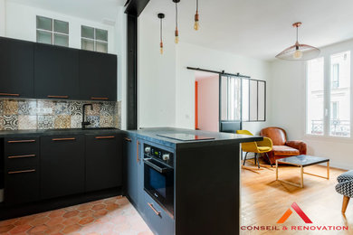 パリにある高級な小さなコンテンポラリースタイルのおしゃれなキッチン (アンダーカウンターシンク、インセット扉のキャビネット、黒いキャビネット、ラミネートカウンター、マルチカラーのキッチンパネル、セラミックタイルのキッチンパネル、パネルと同色の調理設備、セメントタイルの床、赤い床、黒いキッチンカウンター) の写真
