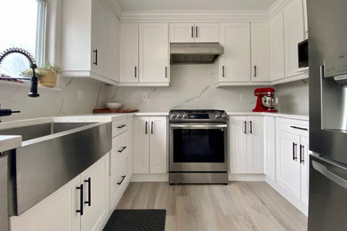 Inspiration for a mid-sized contemporary u-shaped porcelain tile and beige floor eat-in kitchen remodel in Toronto with a farmhouse sink, shaker cabinets, white cabinets, quartz countertops, white backsplash, quartz backsplash, stainless steel appliances and white countertops