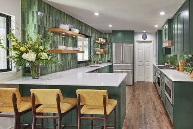 ダラスにある高級な中くらいなモダンスタイルのおしゃれなキッチン (アンダーカウンターシンク、シェーカースタイル扉のキャビネット、緑のキャビネット、珪岩カウンター、緑のキッチンパネル、磁器タイルのキッチンパネル、シルバーの調理設備、淡色無垢フローリング、アイランドなし、茶色い床、白いキッチンカウンター) の写真