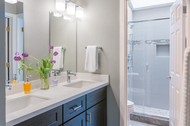 Design ideas for a transitional bathroom in Seattle with shaker cabinets, brown cabinets, an alcove shower, gray tile, grey walls, an undermount sink, a hinged shower door and white benchtops.
